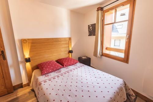 a bedroom with a bed with red pillows and a window at Le Rioumajou 1 - Grand T6 - Piscine - Centre St Lary in Saint-Lary-Soulan