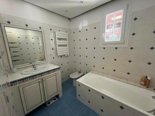 une salle de bain avec une baignoire, un lavabo et un miroir dans l'établissement Maison familiale, grand jardin, à La Ferté-Imbault