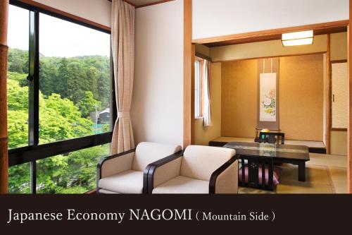 a room with two chairs and a table and a large window at Yamanaka Onsen Kissho Yamanaka in Kaga
