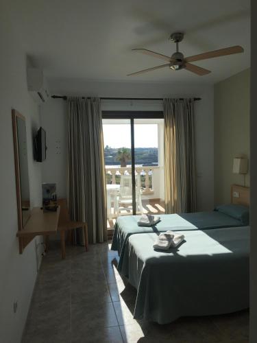 a bedroom with two beds and a large window at Hostal Sa Prensa in Ciutadella