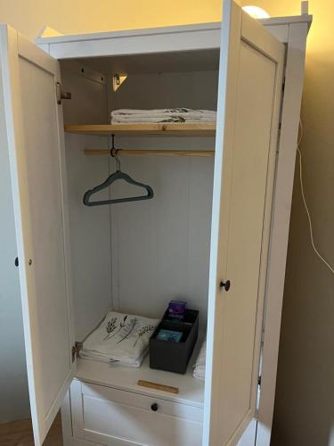 a white closet with a door open with a shelf at Lágholt 16 in Stykkishólmur