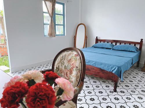 1 dormitorio con 1 cama, 1 silla y flores en SIGNATURE by LAZÁNIA, en Tây Ninh