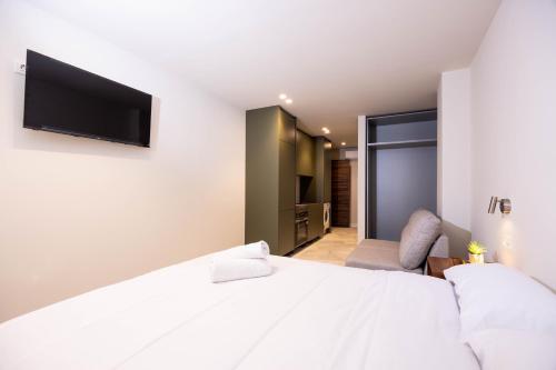 Cette chambre comprend un lit blanc et une télévision murale. dans l'établissement Apartamentos Turísticos Insulae , by CartagenaSpain, à Carthagène