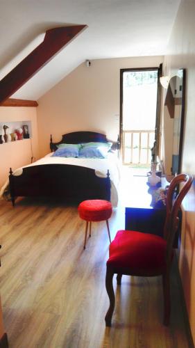 une chambre avec un grand lit et une chaise rouge dans l'établissement Aou Routé, à Auriébat