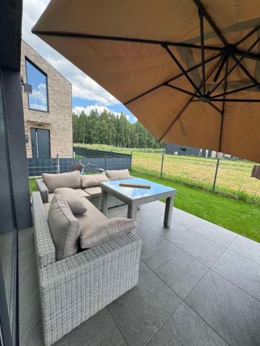 a patio with a couch and a table and an umbrella at SeasideSpa appartment Jakuzzi Swimming pool in Palanga