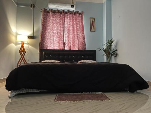 a black bed in a bedroom with a window at Beltola serenity homestay in Guwahati