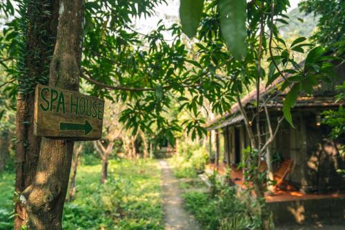 a sign on a tree in front of a house at Chay Lap Farmstay Phong Nha in Ðá Lòn