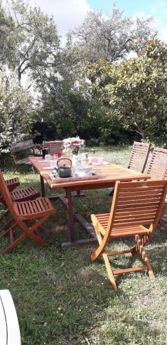 een houten picknicktafel met twee stoelen en een tafel met een kom erop bij La Maison Poésie in Blay