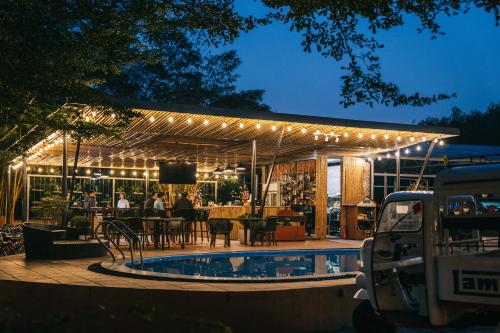 a patio with a swimming pool and a building with lights at Chay Lap Farmstay Phong Nha in Ðá Lòn