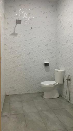 a white bathroom with a toilet in a room at Bilik Umar in Gerik