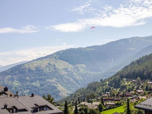 a kite flying in the sky over a village at Apartment Valaisia 34A by Interhome in Nendaz