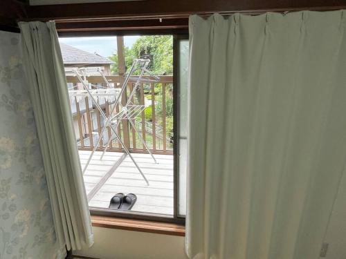 a window with curtains in front of a deck at 2階建1棟貸しの寝室4部屋 無料高速Wi-Fi in Yokohama