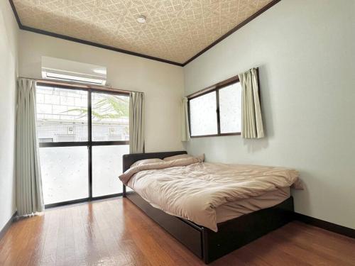 a bedroom with a bed and two windows at 2階建1棟貸しの寝室4部屋 無料高速Wi-Fi in Yokohama