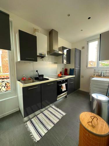 une cuisine avec des armoires noires et blanches et un évier dans l'établissement La vogue studio - proche gare RER E, à Villemomble