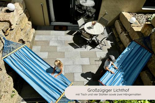 a man and a girl sitting on a blue hammock at INVITA Natur-Chalets - Familienurlaub im Schwarzwald in Bad Dürrheim
