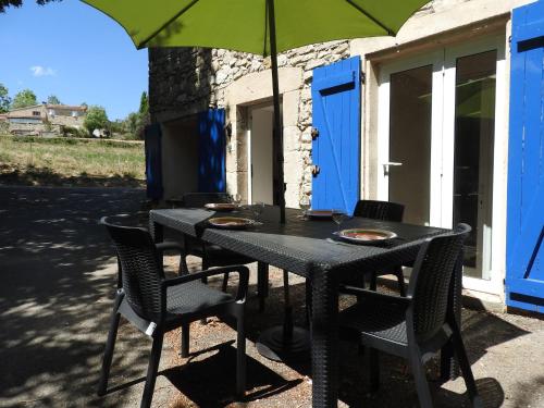 une table noire avec des chaises et un parasol dans l'établissement Holiday Home Maison de Village Serena by Interhome, à Limans