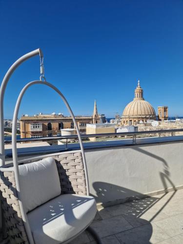 a chair on a roof with a view of the city at The Embassy Valletta Hotel in Valletta