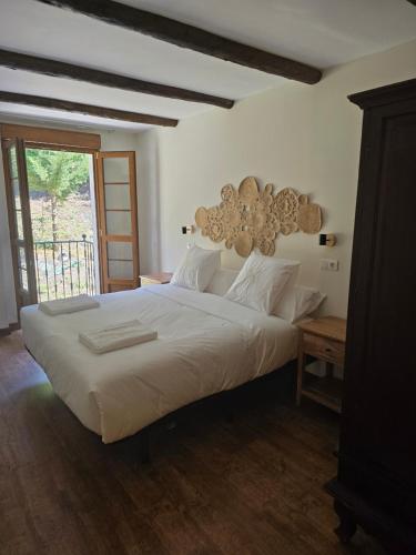 a bedroom with a large white bed and a window at Hotel Rural Valle de Cuaña in Santibáñez de Murias