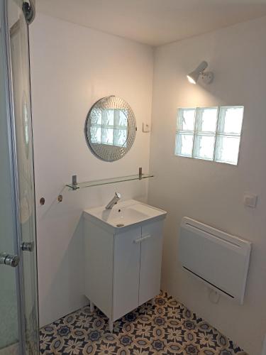 une salle de bain blanche avec un lavabo et un miroir dans l'établissement Le Roi des chats, gîte proche de Beauval et des châteaux, à Mareuil-sur-Cher