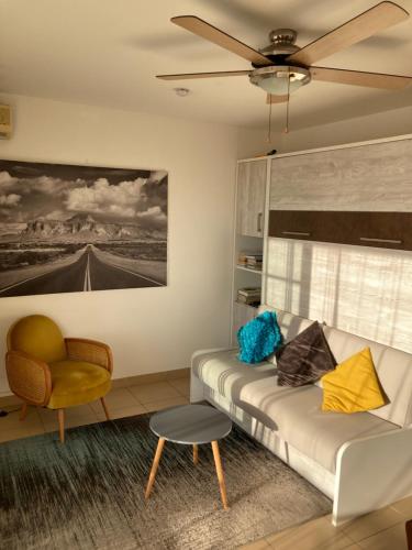 a living room with a couch and a ceiling fan at La Maloyette in La Possession