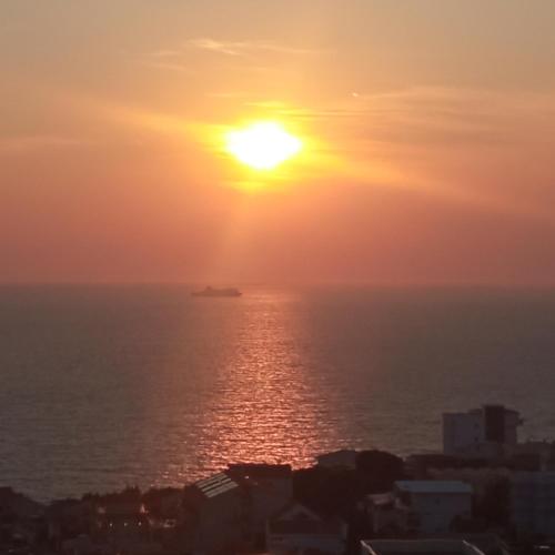 a sunset over the ocean with a ship in the distance at APARTMANI LUX SEA in Utjeha