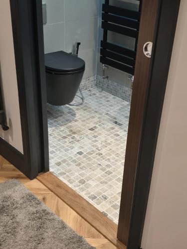 a bathroom with a black toilet and a tile floor at Luxury Non Smoking 2 bedroom retreat in Norfolk in Attleborough