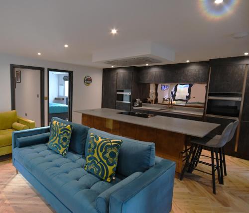 a living room with a blue couch and a kitchen at Luxury Non Smoking 2 bedroom retreat in Norfolk in Attleborough