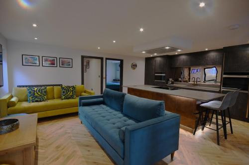 a living room with a blue couch and a kitchen at Luxury Non Smoking 2 bedroom retreat in Norfolk in Attleborough