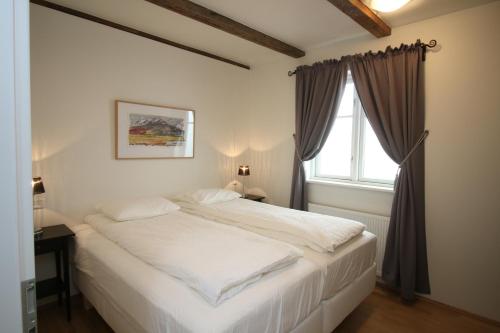 a white bed in a bedroom with a window at Acco Ice Apartments in Akureyri