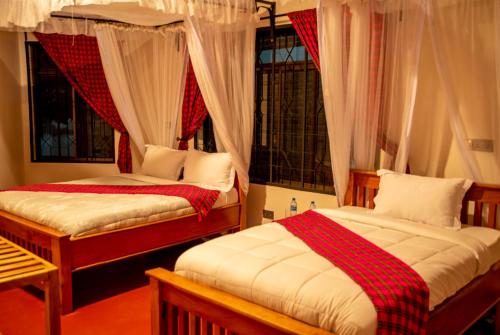 a bedroom with two beds and a window at Siafu Serenity Lodge in Mto wa Mbu