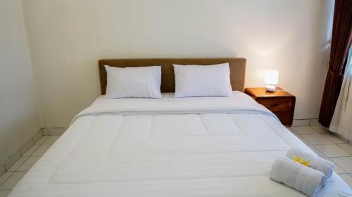a large white bed with two pillows and a night stand at Hotel pondok putri in Batukaras