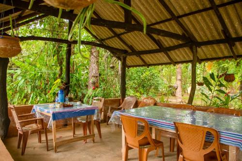 a patio with tables and chairs under a roof at Nice View Lodge in Sigiriya