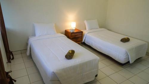 two beds in a room with a lamp on a table at Hotel pondok putri in Batukaras