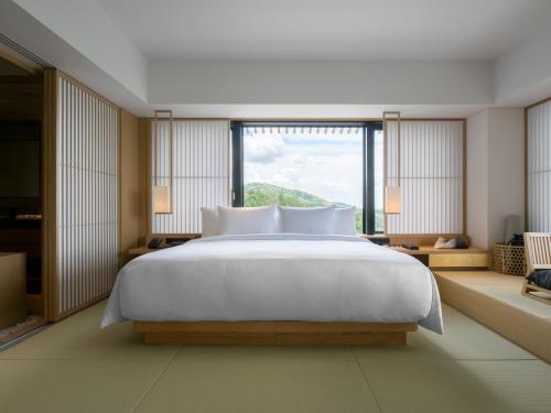 a bedroom with a large white bed and a large window at Banyan Tree Higashiyama Kyoto in Kyoto