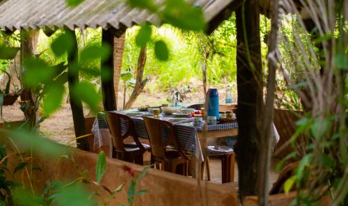 a wooden table with chairs in a garden at Nice View Lodge in Sigiriya