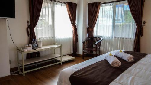 a bedroom with a bed and a chair and windows at Hotel pondok putri in Batukaras