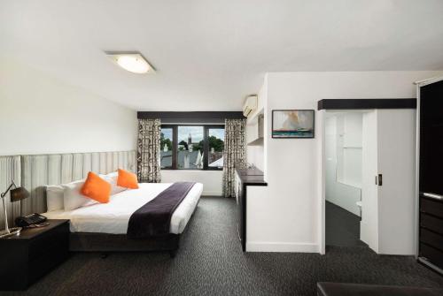 a hotel room with a bed with orange pillows at Comfort Hotel East Melbourne in Melbourne