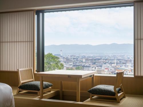 a room with a table and two chairs and a large window at Banyan Tree Higashiyama Kyoto in Kyoto
