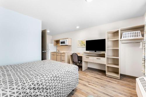 a bedroom with a bed and a desk with a tv at WoodSpring Suites Bluffdale Salt Lake City in Bluffdale