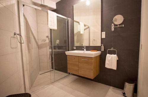 a bathroom with a shower and a sink and a mirror at Mosta Central City Residences by 360 Estates in Mosta