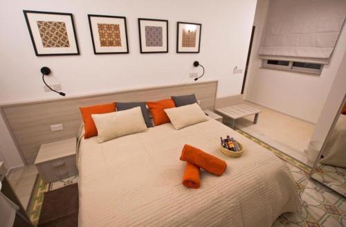 a bedroom with a large white bed with orange pillows at Mosta Central City Residences by 360 Estates in Mosta