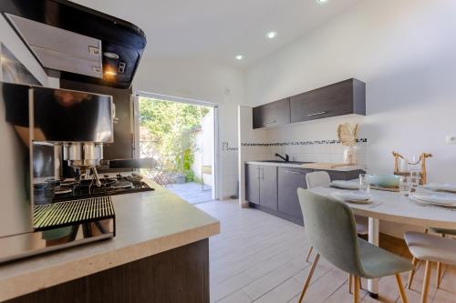 une cuisine avec une cuisinière et une table avec des chaises dans l'établissement Maison Élégante avec Jardin I Centre de Cognac, à Cognac