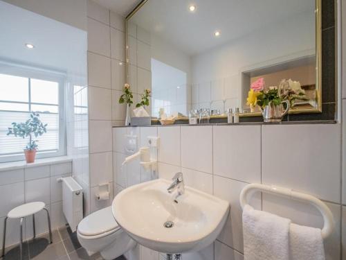 a white bathroom with a sink and a toilet at Posthotel Monegro in Steinfurt