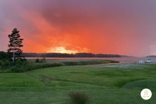 a sunset over the water at a golf course at Villa Eden - Design-Sea-Pool-Sauna in Kemionsaari
