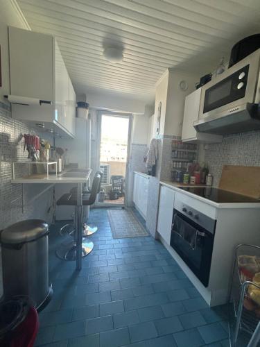 une cuisine avec des armoires blanches et une table et des chaises dans l'établissement Chambre moderne chez l'habitant, à Toulon