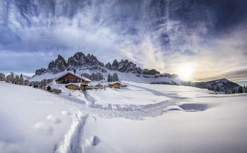 a snow covered mountain with a lodge in the background at Taubers Unterwirt Aktiv & Vitalhotel in Feldthurns
