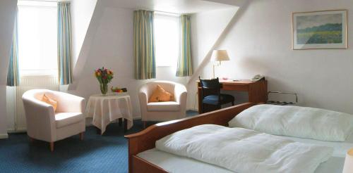 a hotel room with a bed and a chair at Posthotel Monegro in Steinfurt