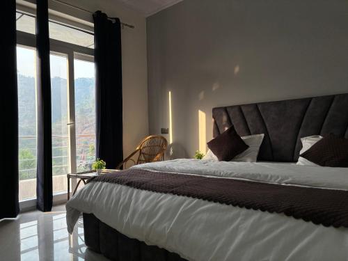 a bedroom with a large bed with a large window at Mount Valley in Chamba