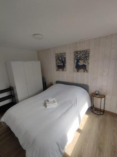 - un lit blanc dans une chambre avec 2 photos sur le mur dans l'établissement ThiLuCha Le ThiLu ALPE D'HUEZ gd domaine à Allemont, à Allemont