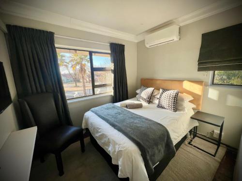 a bedroom with a bed and a chair and a window at Modern Goldfields Apartments in Virginia